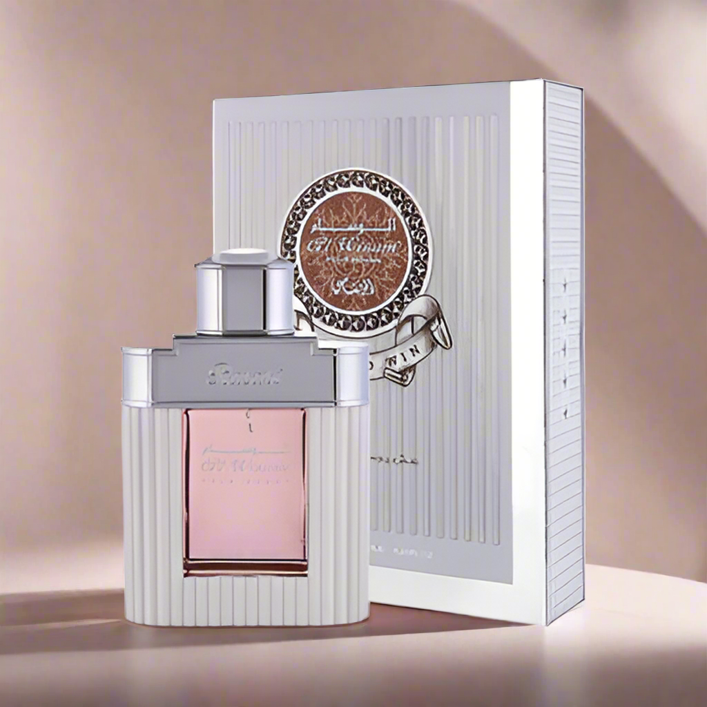 Perfume bottle with pink cap and silver accents, placed in front of a matching box on a beige background.