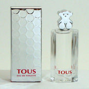 A sealed box of TOUS brand eau de toilette for women alongside a clear glass bottle with a silver cap, both displaying the brand name 'TOUS'.