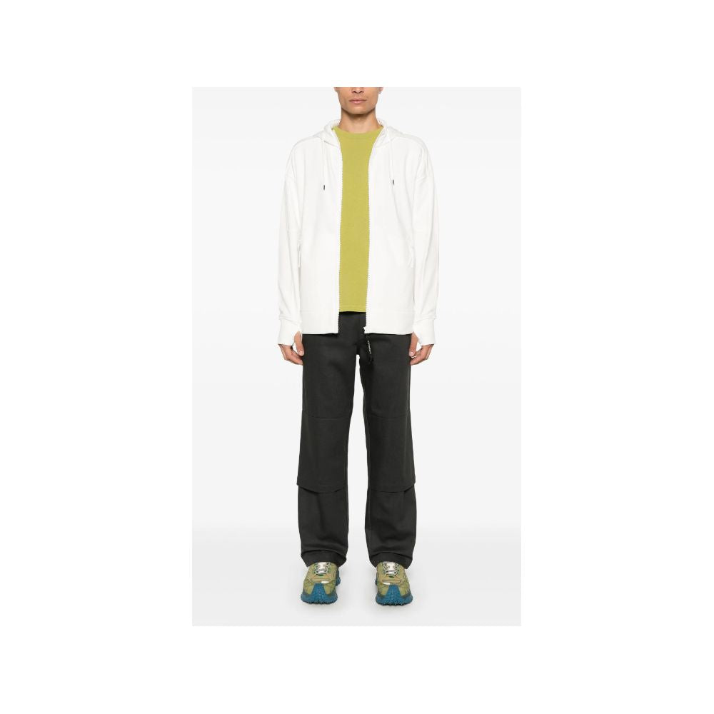 Man in a white cotton sweater with green shirt and black pants for C.P. Company style