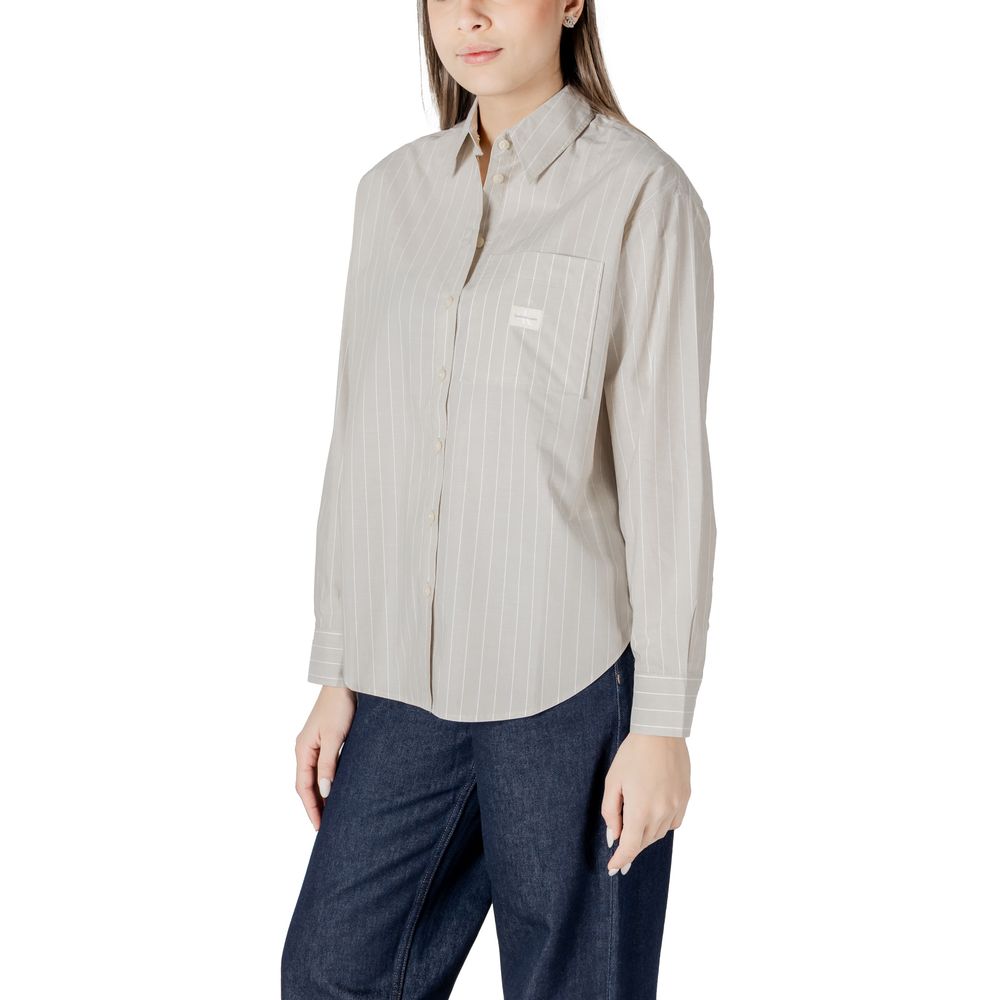 Woman wearing a Calvin Klein Jeans beige cotton sweater with a striped button-down shirt