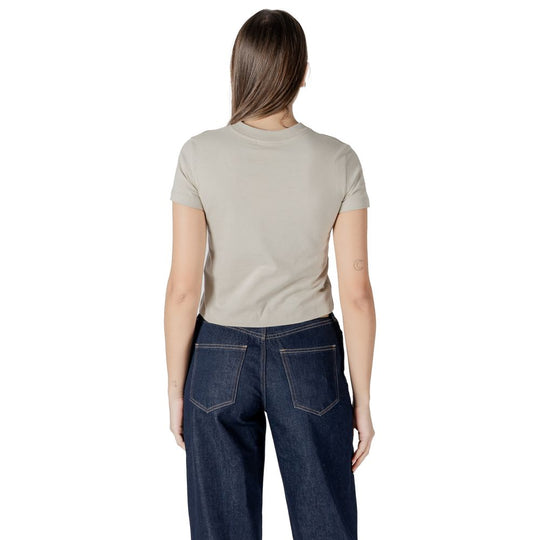 Woman in beige cotton top and dark blue jeans from Calvin Klein Jeans collection