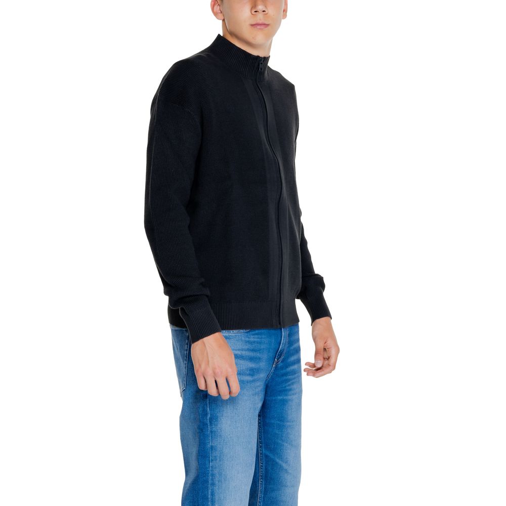 Man in Calvin Klein Jeans Black Cotton Rigenerato Cardigan and blue jeans