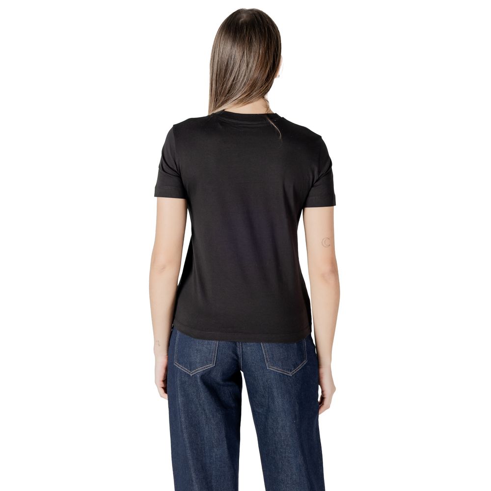 Woman in black t-shirt and blue jeans wearing Calvin Klein Jeans Cotton Rigenerato Tops