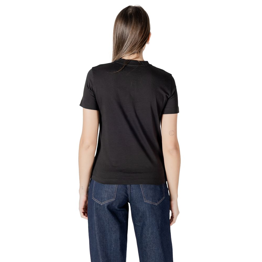 Woman in Calvin Klein Jeans black cotton top and blue jeans, showcasing casual style