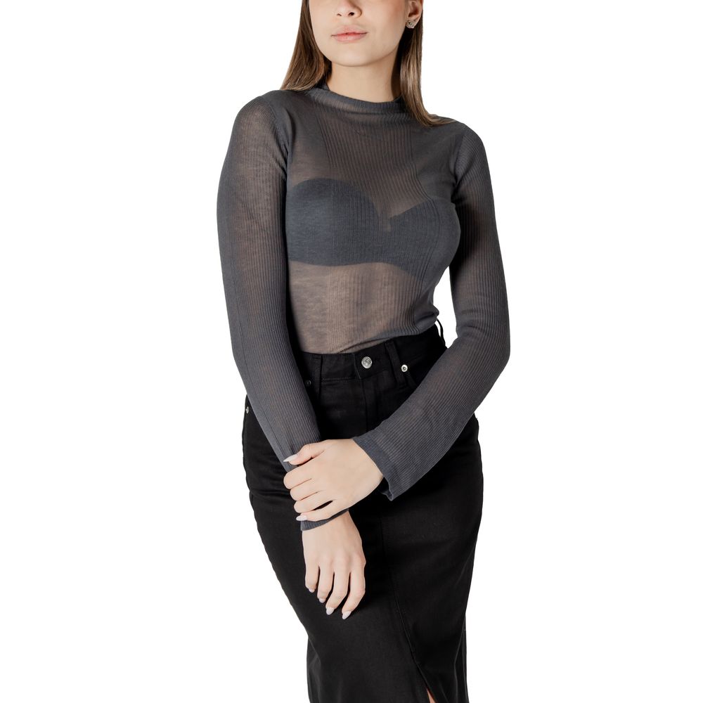 Woman in sheer gray long-sleeved top and black skirt from Calvin Klein Jeans collection