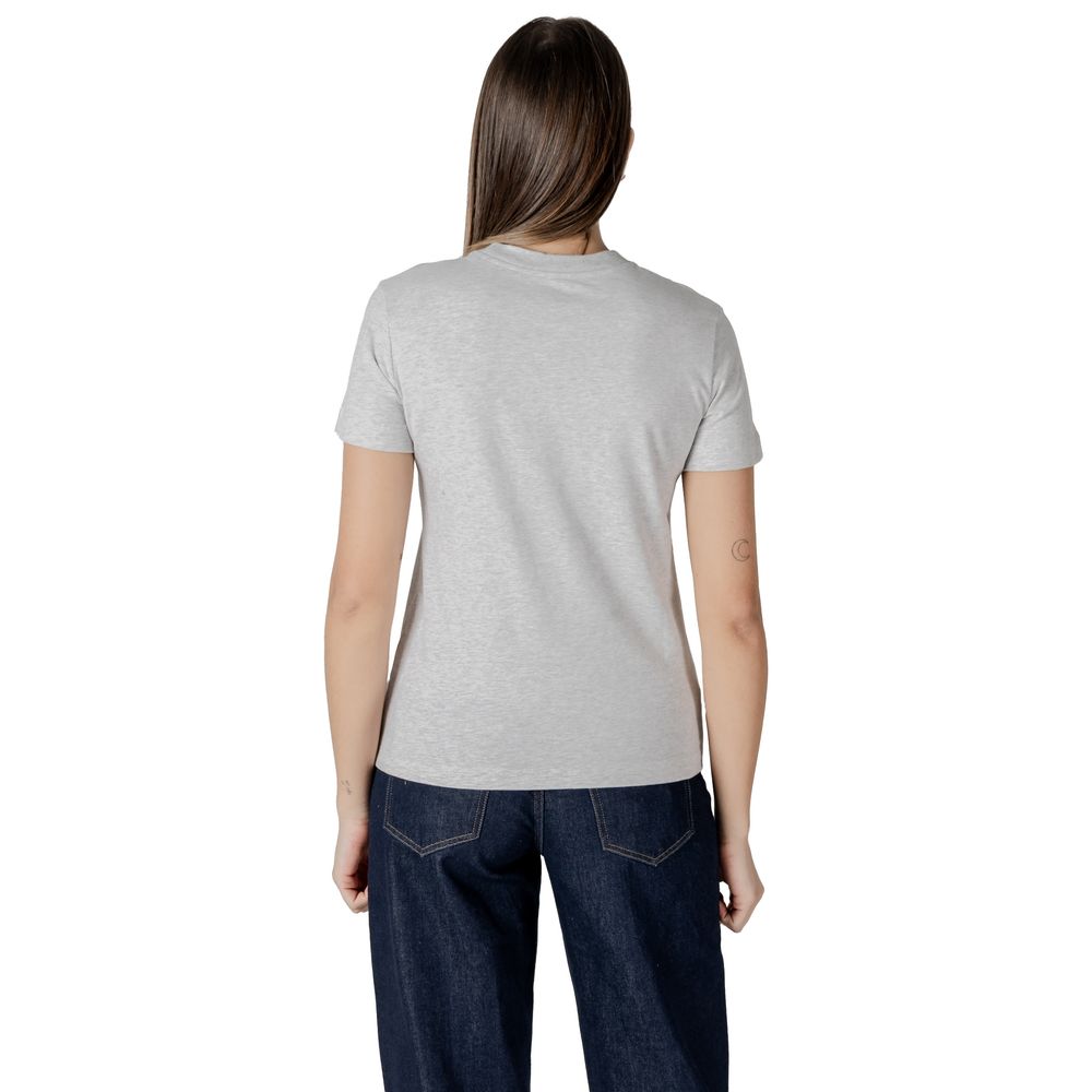 Woman in gray cotton top and dark blue jeans from Calvin Klein Jeans collection